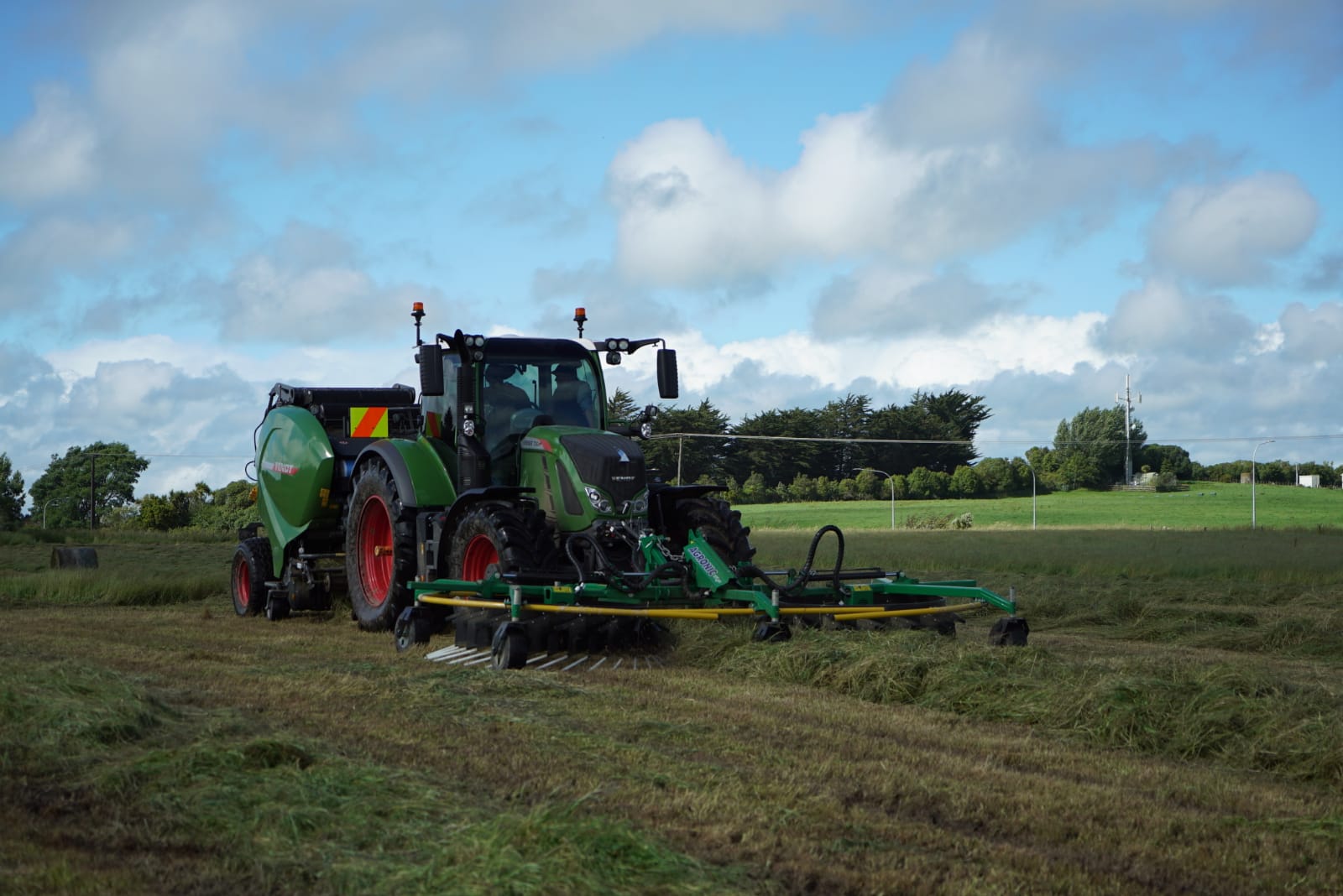 A tractor raking and baling at the same time